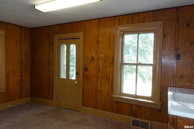 carpeted entrance foyer with wood walls