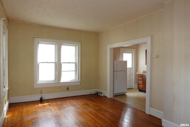 empty room featuring plenty of natural light, a baseboard radiator, and light wood-type flooring