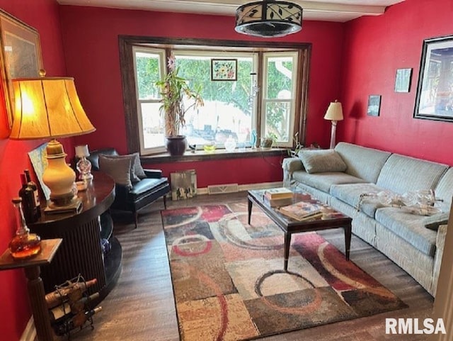 living area featuring a wealth of natural light, visible vents, and wood finished floors