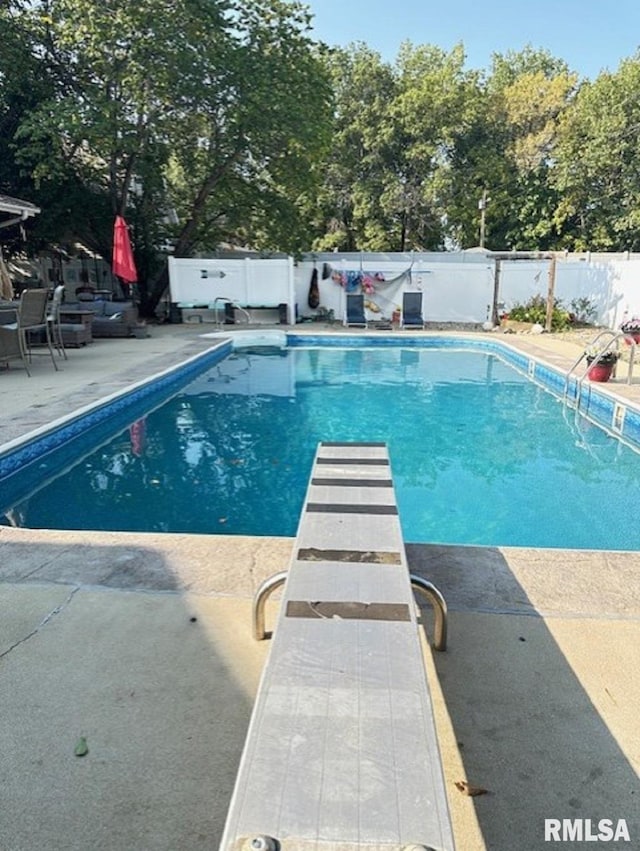 view of pool with a patio, a fenced in pool, a fenced backyard, and a diving board