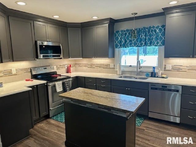 kitchen with appliances with stainless steel finishes, a kitchen island, pendant lighting, and dark hardwood / wood-style flooring