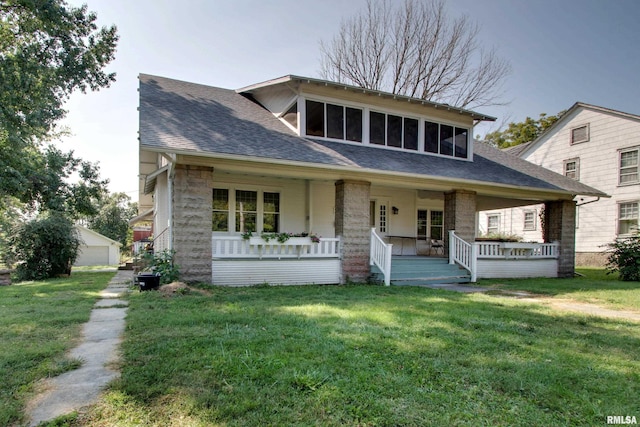 view of front of property featuring a front yard, a garage, an outdoor structure, and a porch