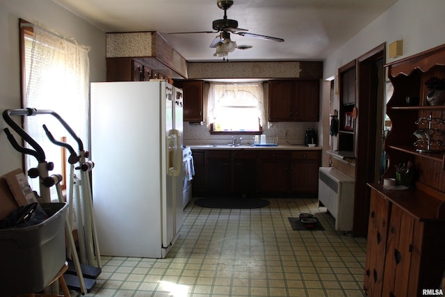 kitchen featuring radiator heating unit, stainless steel range, ceiling fan, and white fridge with ice dispenser