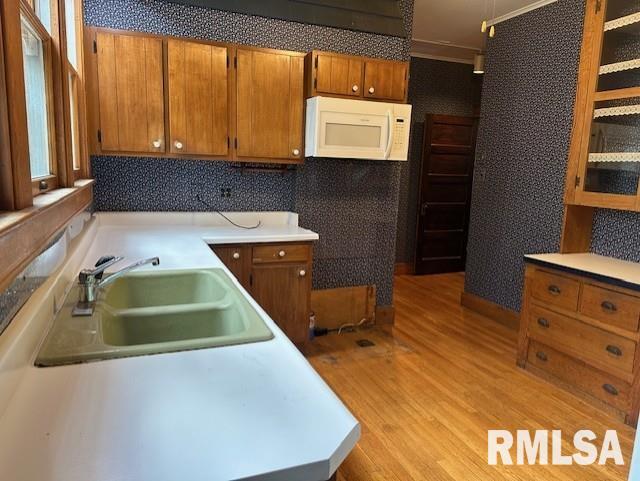 kitchen featuring light wood-type flooring, crown molding, and sink