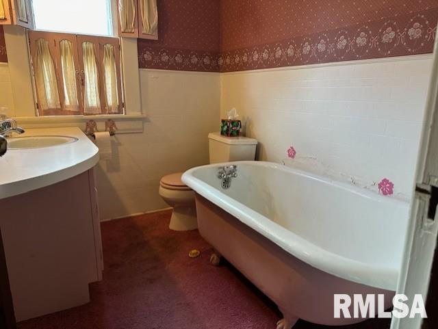 bathroom featuring vanity, toilet, and a tub