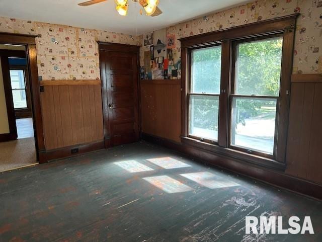 unfurnished room featuring wood walls and ceiling fan