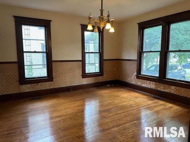 empty room with a notable chandelier and hardwood / wood-style flooring