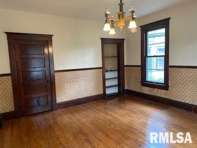 spare room with plenty of natural light, a chandelier, and dark hardwood / wood-style floors