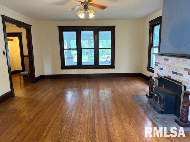 unfurnished living room featuring ceiling fan, a fireplace, and dark hardwood / wood-style floors