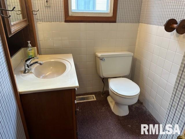 bathroom featuring vanity, toilet, and tile walls