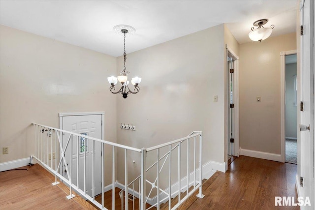 corridor with wood-type flooring and a notable chandelier