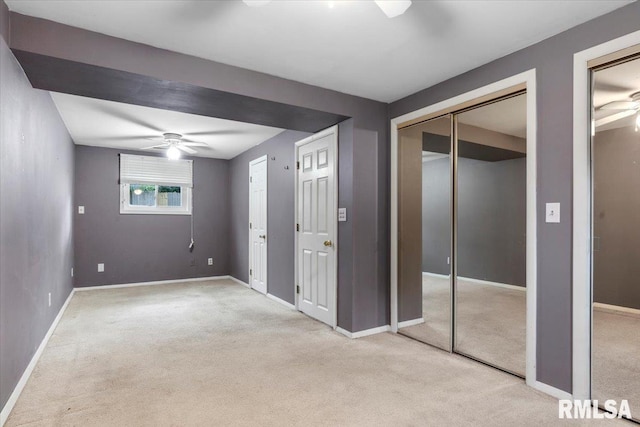 unfurnished bedroom with ceiling fan, light carpet, and two closets