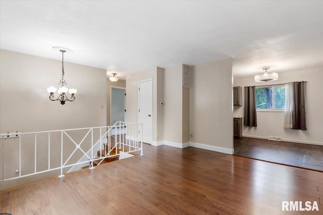 unfurnished room with dark wood-type flooring and a notable chandelier