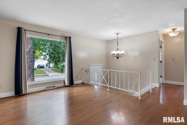 empty room featuring a chandelier and wood-type flooring