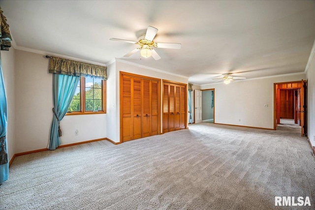 unfurnished bedroom featuring crown molding, two closets, ceiling fan, and carpet floors