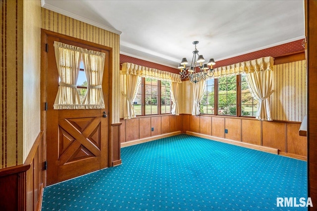 interior space featuring ornamental molding, a chandelier, wood walls, and carpet flooring