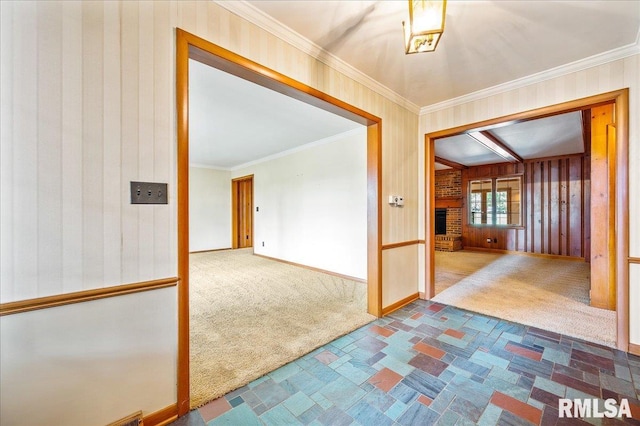 hallway featuring wooden walls, carpet, and crown molding