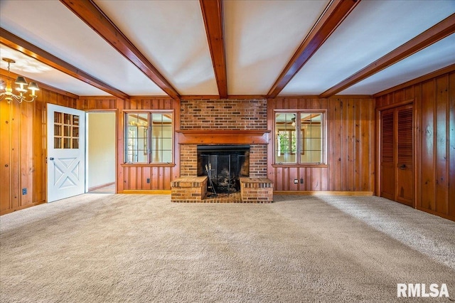 unfurnished living room featuring wood walls, a fireplace, and beam ceiling