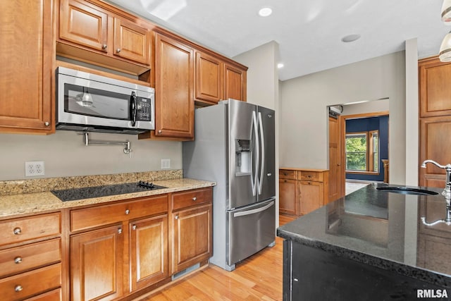 kitchen featuring light stone counters, stainless steel appliances, sink, and light hardwood / wood-style flooring