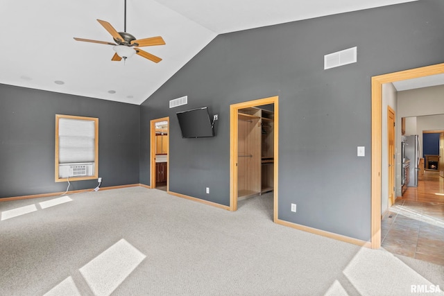 bedroom featuring a closet, ceiling fan, ensuite bathroom, a walk in closet, and light carpet