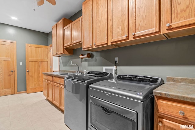 clothes washing area with washing machine and clothes dryer, sink, ceiling fan, and cabinets