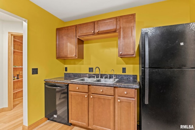 kitchen featuring dark stone counters, black appliances, light hardwood / wood-style floors, and sink