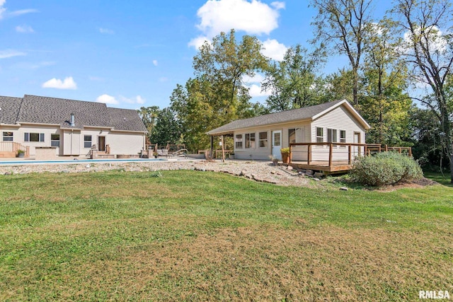 rear view of house with a lawn and a swimming pool side deck