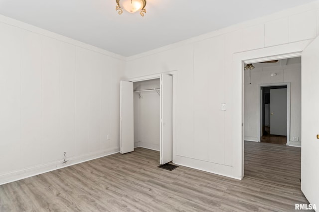 unfurnished bedroom featuring ornamental molding, light wood-type flooring, and a closet