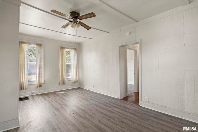 spare room with wood walls, dark hardwood / wood-style flooring, and ceiling fan