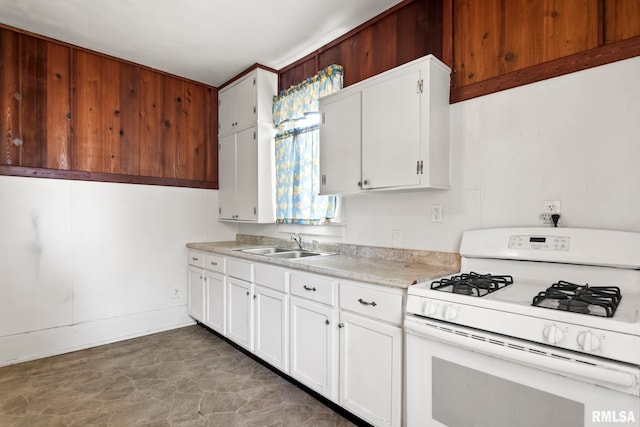 kitchen with sink, gas range gas stove, and white cabinetry