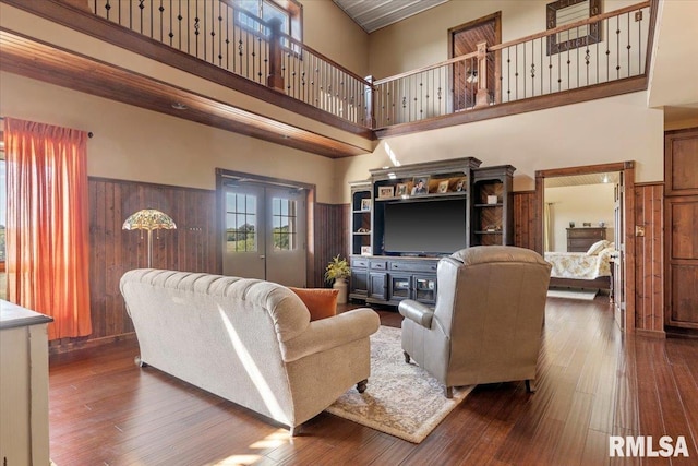 living room featuring a high ceiling, wooden walls, and dark hardwood / wood-style floors