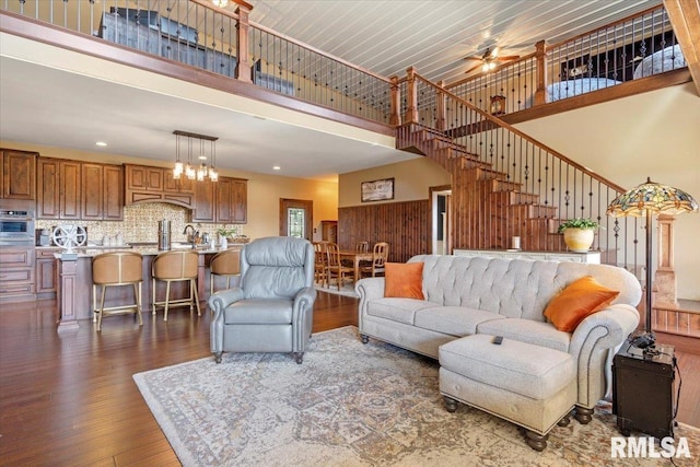 living room featuring a high ceiling, ceiling fan, dark hardwood / wood-style floors, and sink