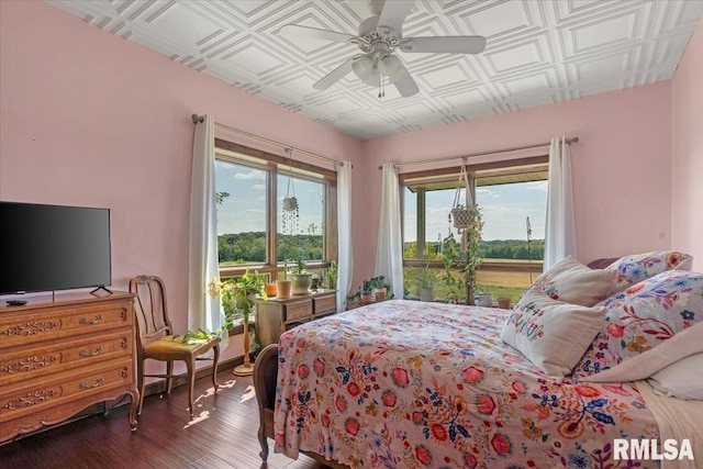 bedroom featuring multiple windows, dark hardwood / wood-style floors, and ceiling fan