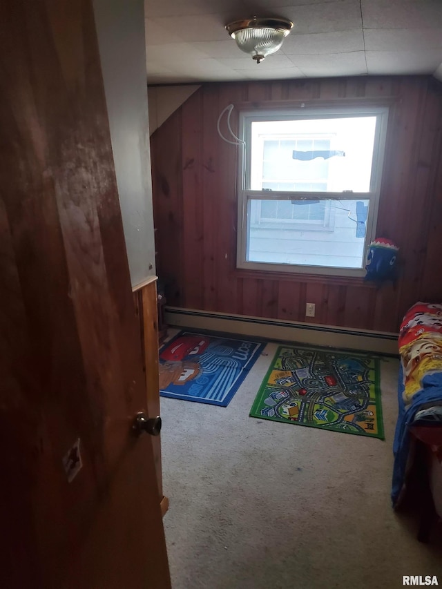 interior space with carpet flooring, wood walls, and baseboard heating