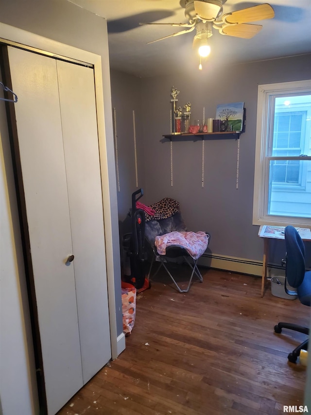 bedroom with ceiling fan, dark wood-type flooring, and a baseboard heating unit