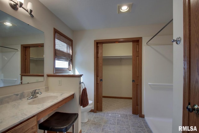 bathroom featuring walk in shower, vanity, and toilet