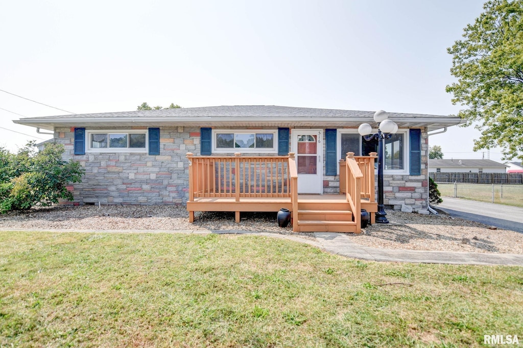 single story home featuring a front lawn, fence, stone siding, and a wooden deck