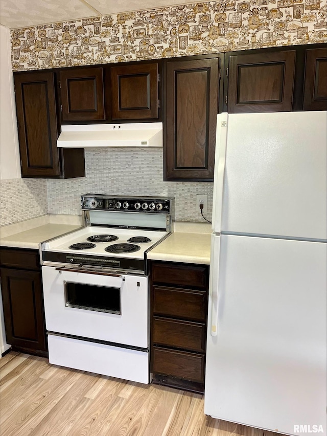 kitchen with dark brown cabinetry, light wood-type flooring, tasteful backsplash, and white appliances