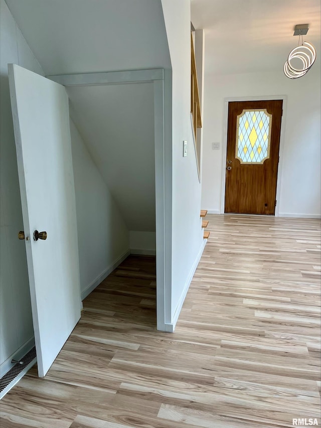 entrance foyer featuring visible vents, light wood-style flooring, vaulted ceiling, and baseboards