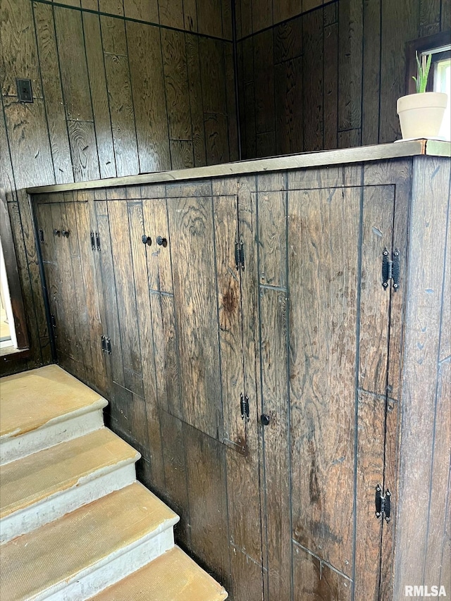 staircase featuring wood walls