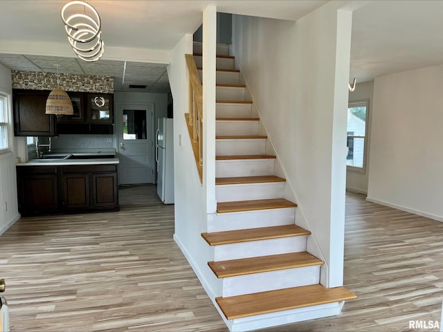 staircase featuring baseboards, visible vents, and wood finished floors
