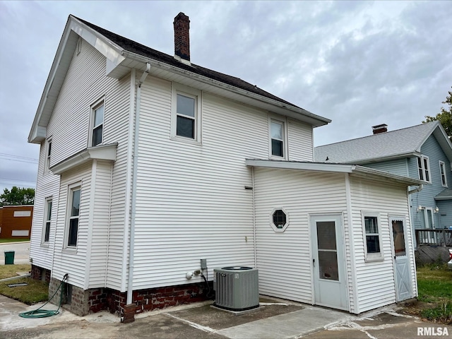 rear view of property with a chimney and central AC unit