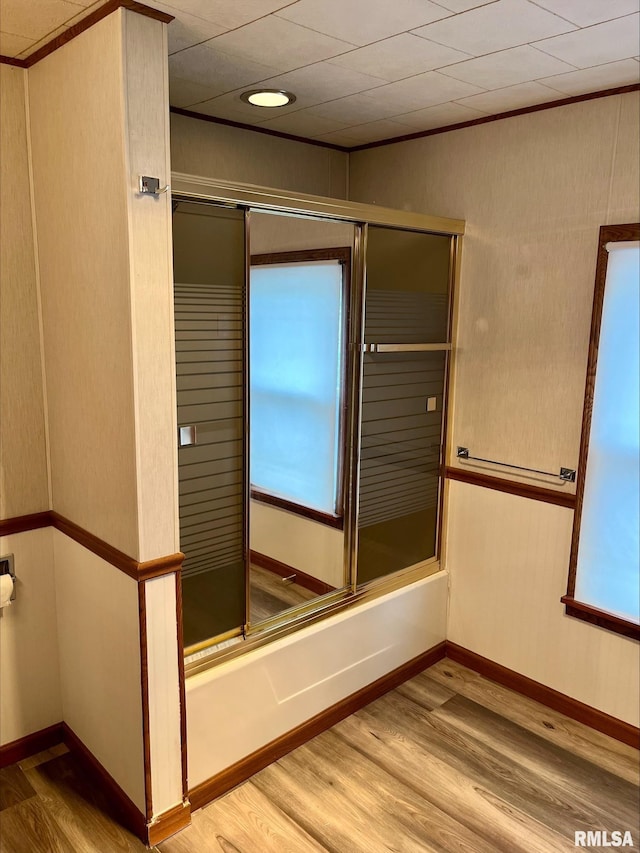 bathroom featuring baseboards, shower / bath combination with glass door, and wood finished floors