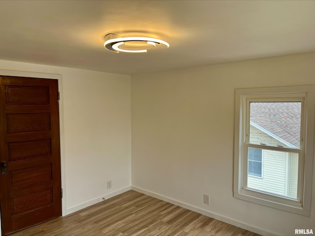 spare room featuring baseboards and light wood finished floors