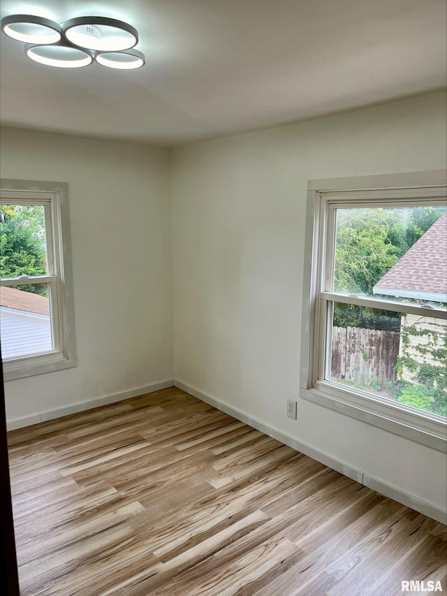 unfurnished room with baseboards, light wood-style floors, and plenty of natural light
