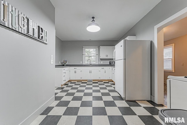 kitchen featuring sink, white fridge, and white cabinetry