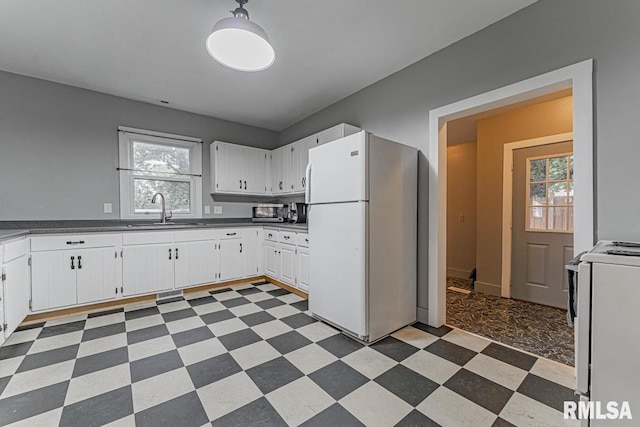 kitchen featuring white cabinets, stove, sink, and white refrigerator