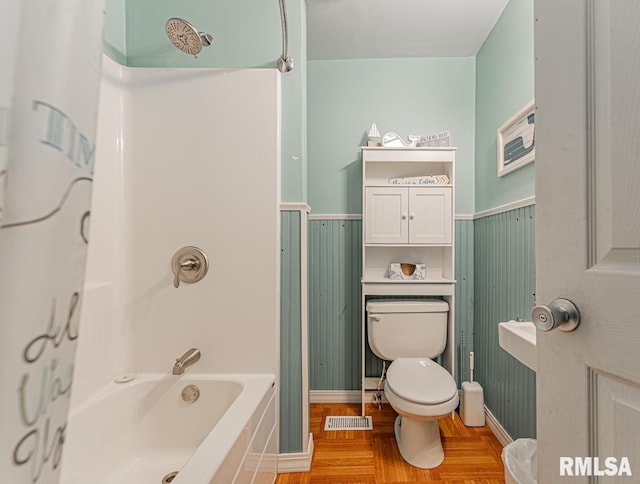 bathroom featuring  shower combination, hardwood / wood-style flooring, and toilet