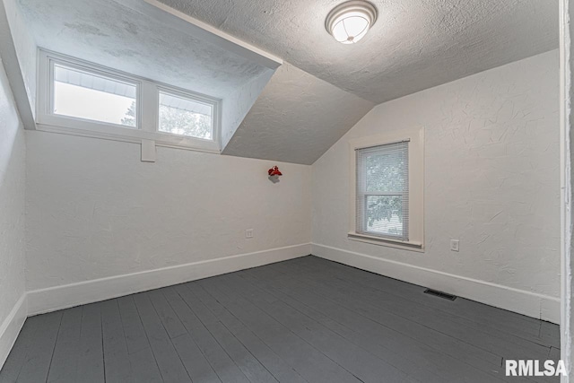 bonus room featuring lofted ceiling, plenty of natural light, and dark wood-type flooring