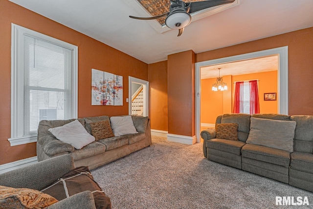 carpeted living room with ceiling fan with notable chandelier